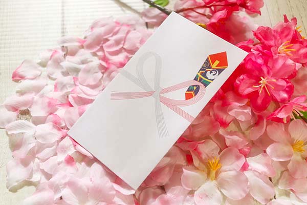 桜の花に囲まれた祝儀袋。お祝い制度のイメージ