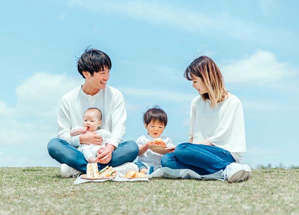 芝生でピクニックを楽しむ家族。育児と両立できる働き方のイメージ