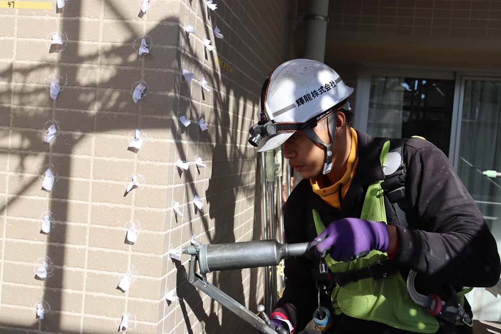 外壁タイルへの注入工事。専用工具で補修材を注入